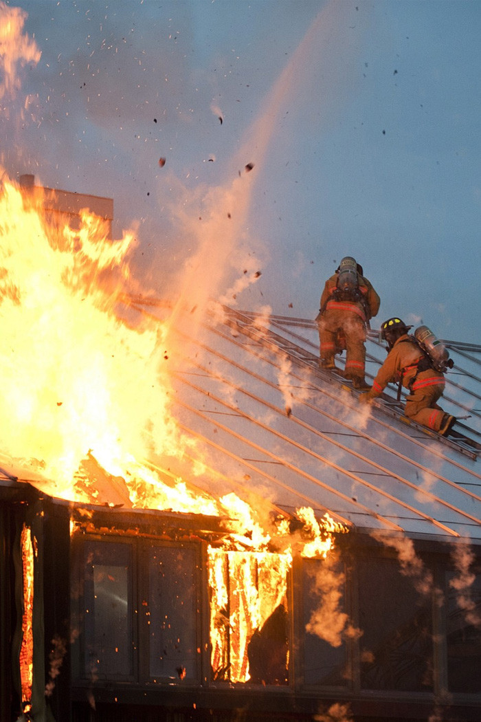 Firefighters on a roof with fire damage