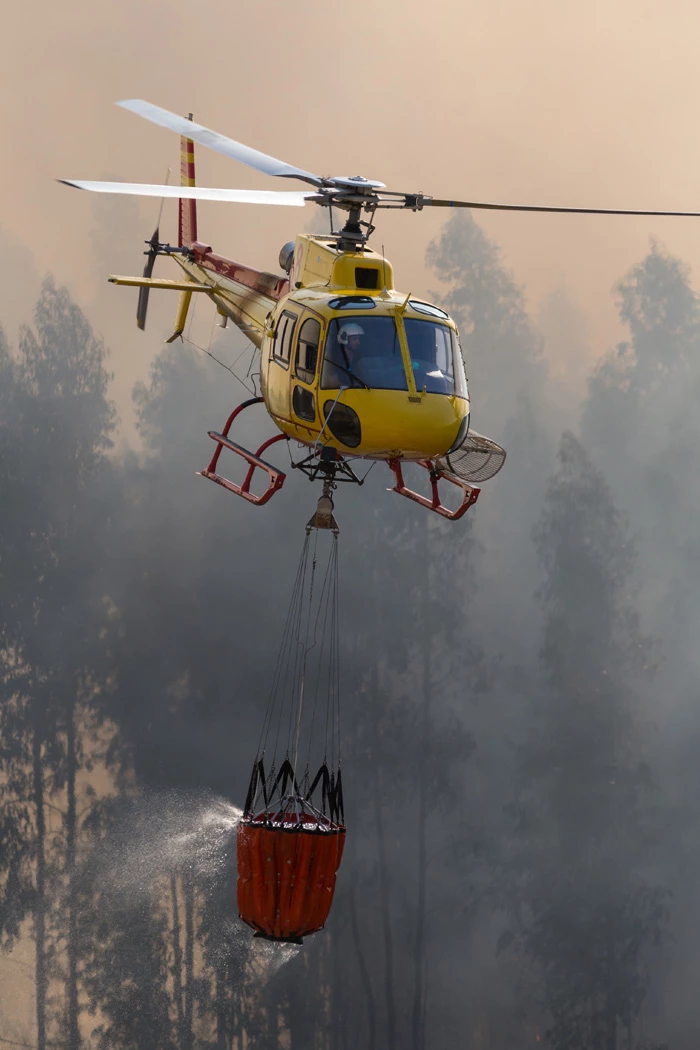 Helicopter flying over wildfire to drop water
